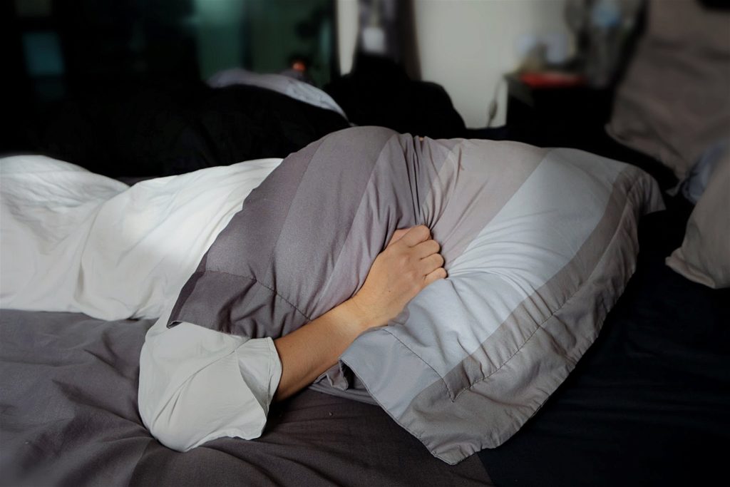 woman with head under pillow